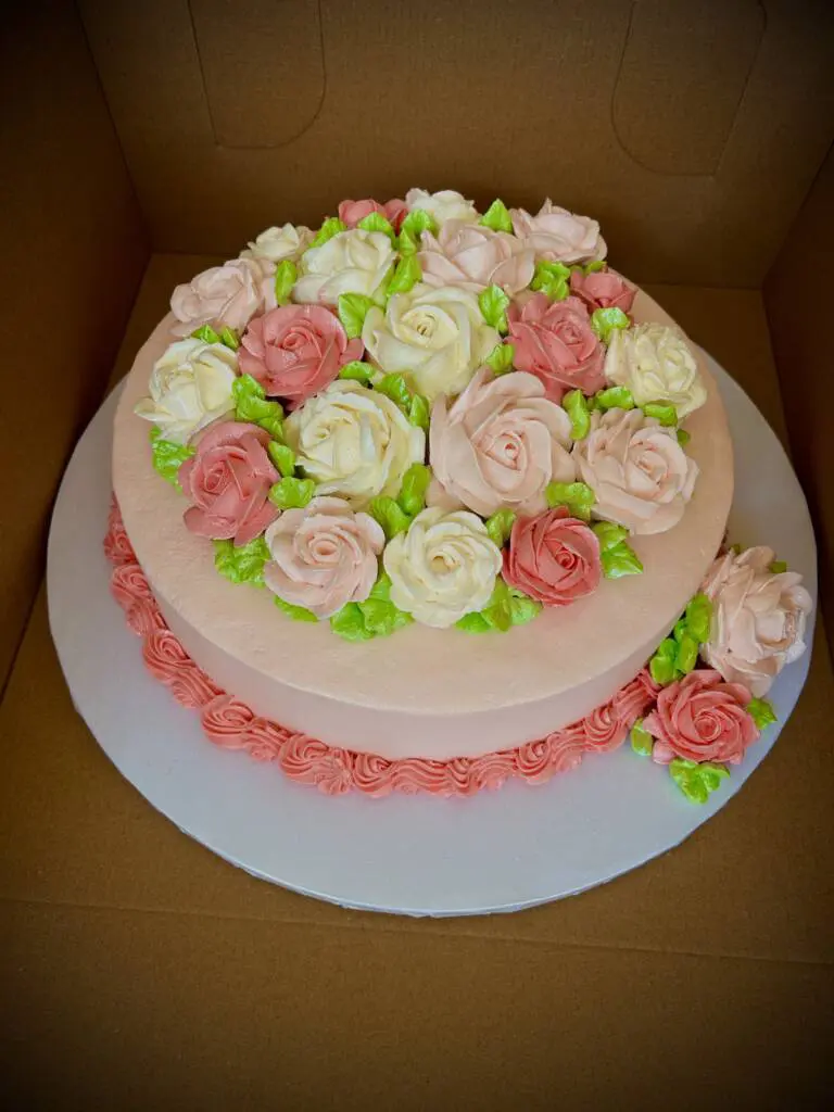 A pink, white, and green cake with flowers on top