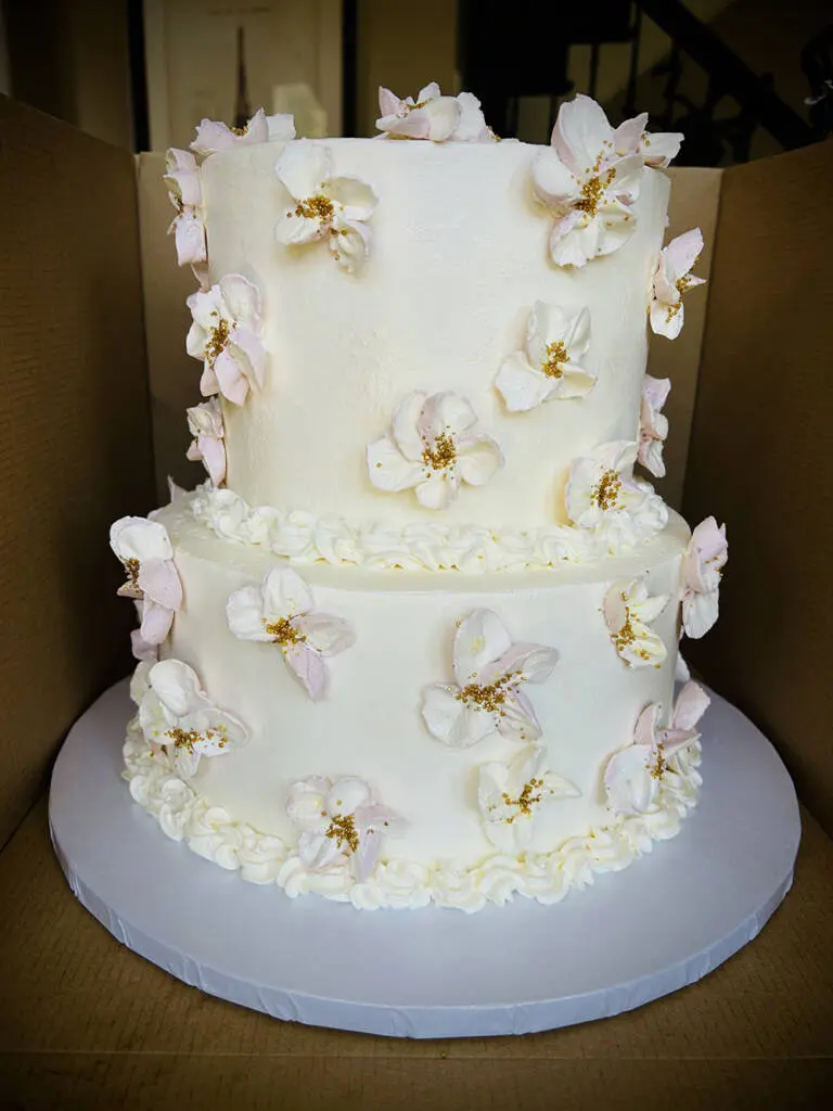 A two-tier cake with white frosting and flowers
