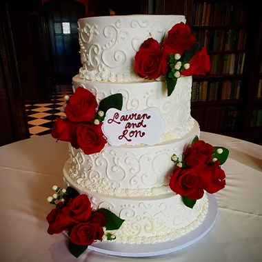 A white four-tier wedding cake with red roses